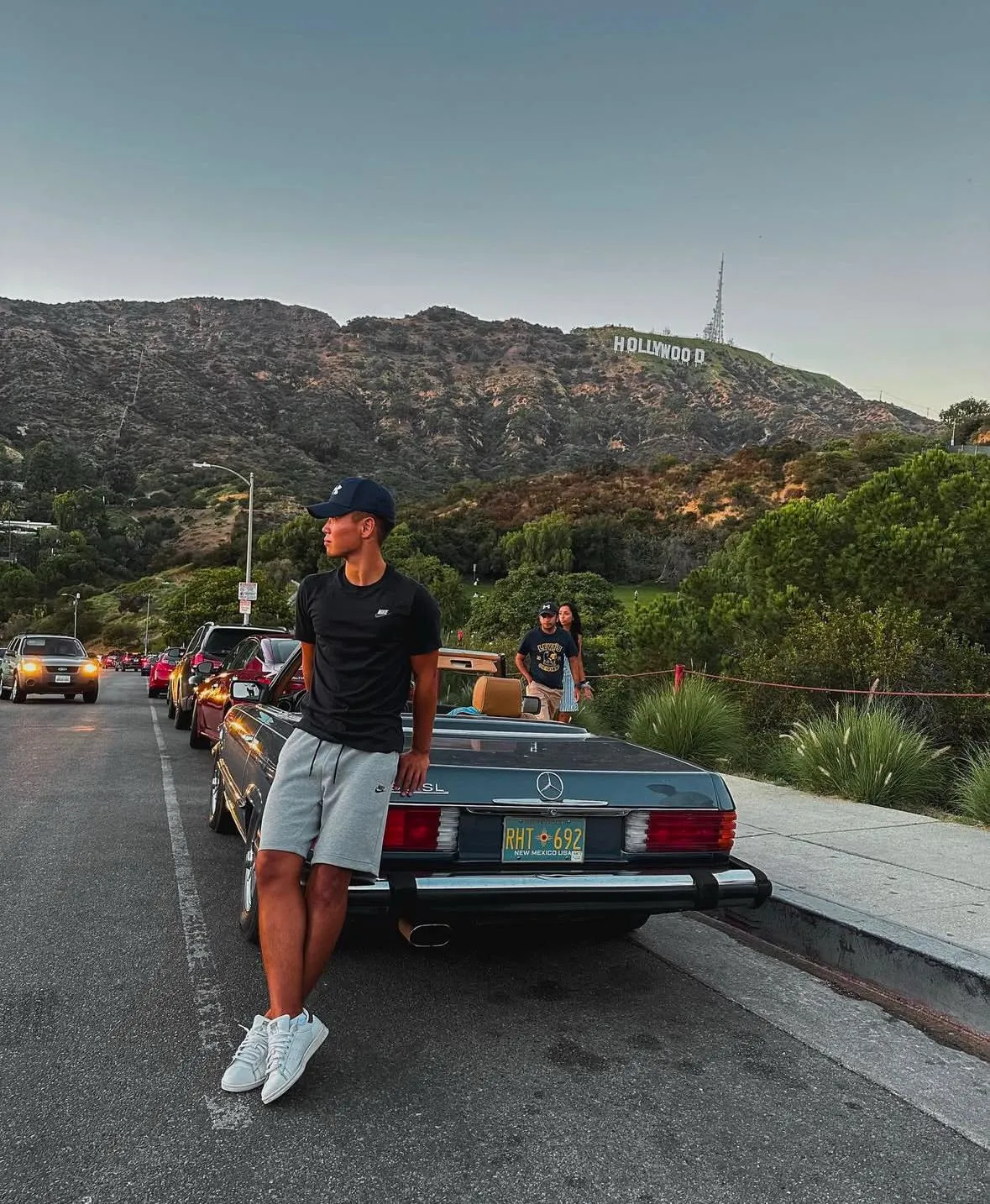 Un ragazzo appoggiato a una decappottabile, la scritta Hollywood sulla collina
