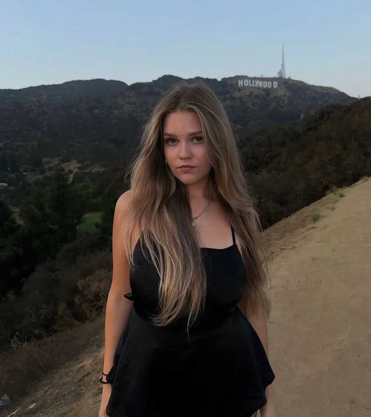 Una ragazza davanti alla scritta Hollywood al tramonto