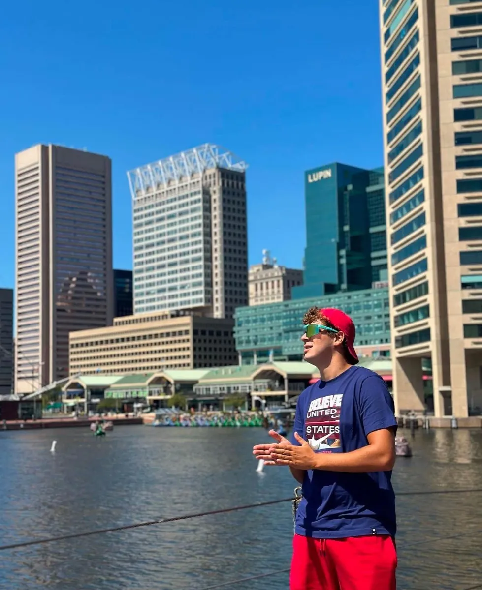 Un ragazzo con lo skyline di Baltimora alle spalle