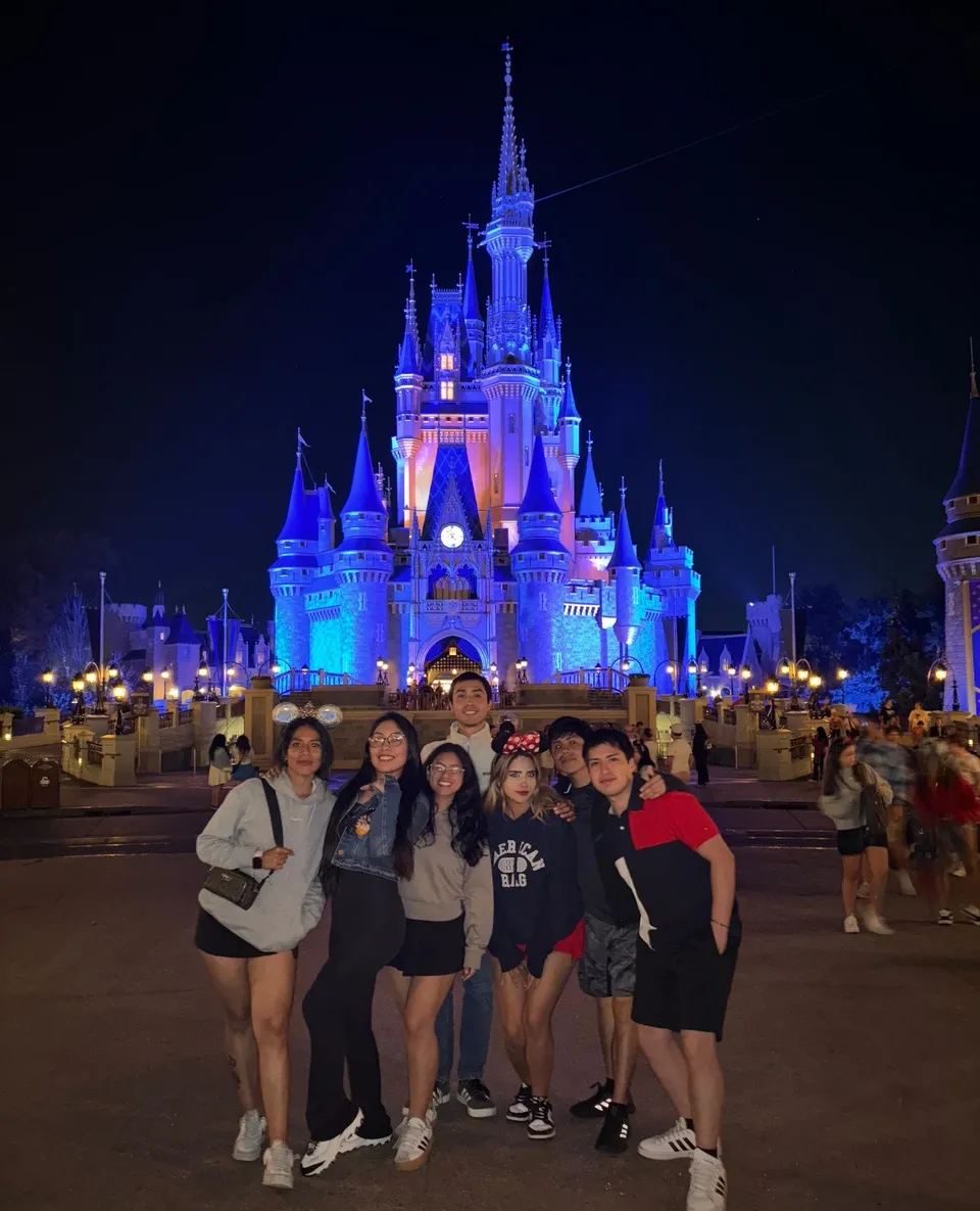 Un gruppo di studenti davanti al castello della Bella Addormentata illuminato di notte, a Disney World