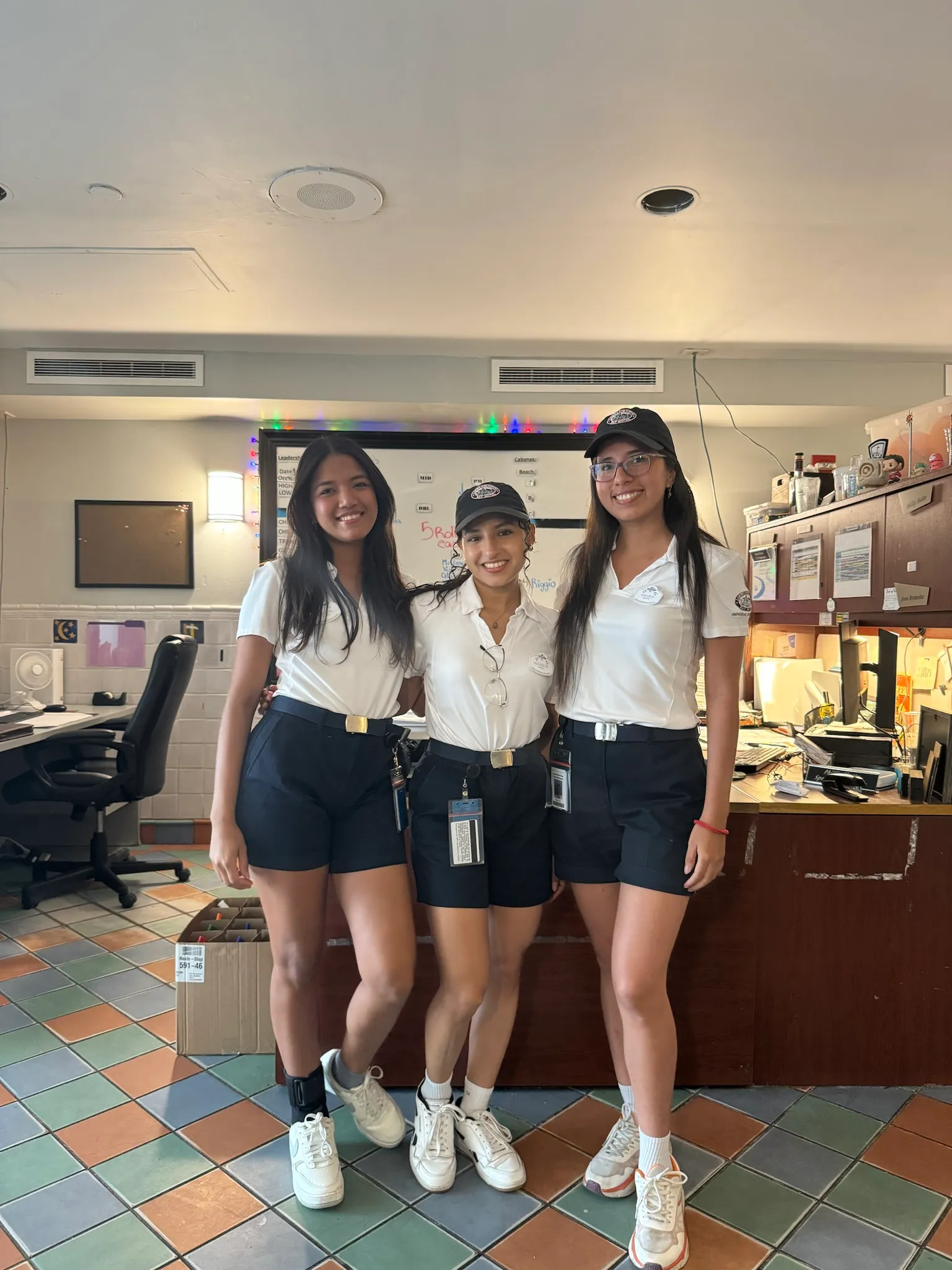 Tre ragazze in camicia bianca dietro il bancone della reception di un hotel